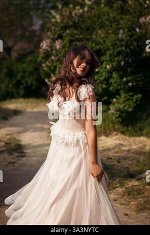 Stunning bride gracefully poses in a spring park, among blossoming trees. exuding elegance, Stock Photo