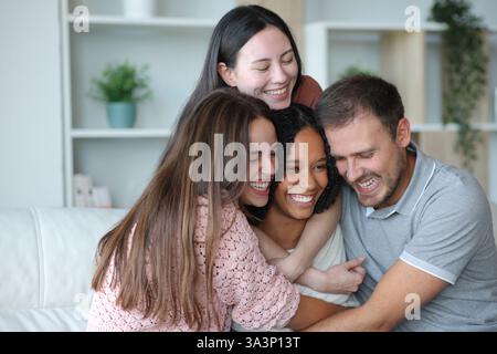 Happy group of best interracial friends hugging sitting on a couch at home Stock Photo