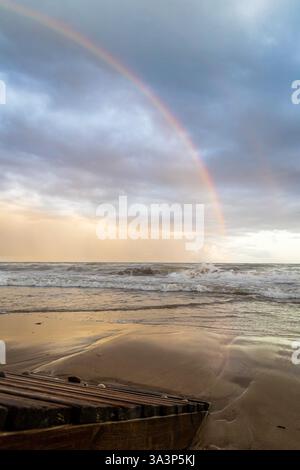 A stunning view of Beach of Tamarit, where ocean waves crash onto the golden sand under a dramatic sky Stock Photo