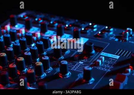 Professional mixing console on black background in neon lights, closeup Stock Photo