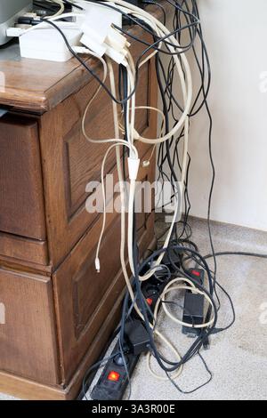 Lot of messy cables on the floor near wooden desk Stock Photo