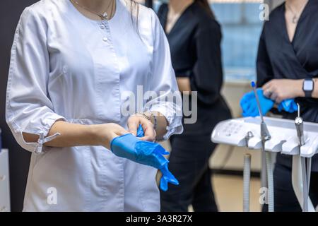 A woman dentist puts a rubber glove on her hand. Dentistry concept. Stock Photo