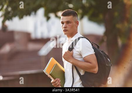 In casual clothes. Young male student is outdoors. Stock Photo