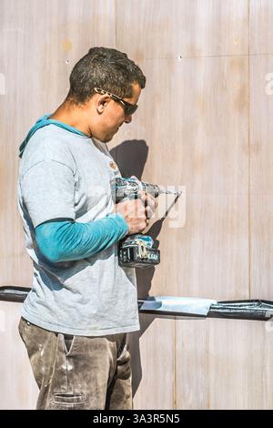 Worker drilling hole into marble fascia - Tours, Indre-et-Loire (37), France. Stock Photo