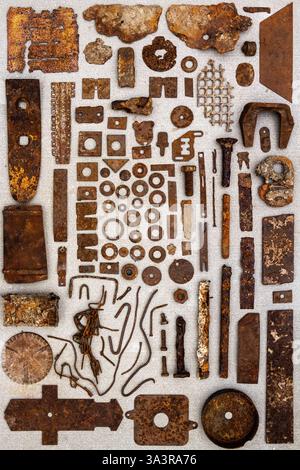 A group of various old rusty parts arranged on a concrete surface. Old rusty nuts, bolts, nails and other parts flay lay on gray background. Stock Photo