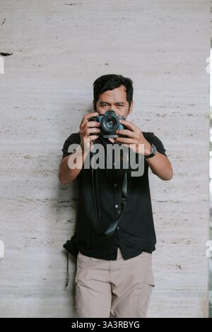 A focused photographer attentively framing a shot using a modern digital camera. The image shows someone enjoying photography with a serious look, hol Stock Photo