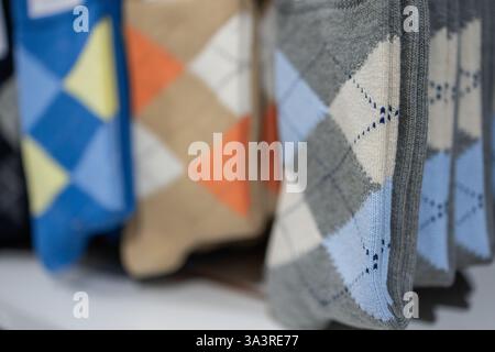 Stack of patterned socks featuring classic argyle design in multiple colors folded uniformly on a retail display highlighting textile texture and geom Stock Photo