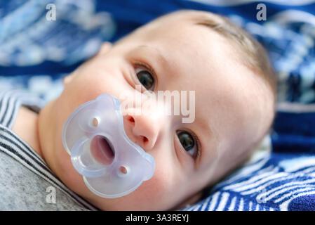 Cute boy laying down on bed and looking at camera Stock Photo