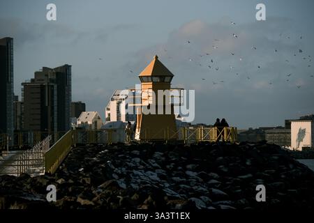 Hofoi yellow lighthouse a landmark overlooking the Faxaflói bay with the high-rise buildings of the city in the background. Stock Photo