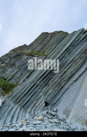 A striking geological formation featuring sharply angled, layered rock cliffs located in the north of Spain. Stock Photo