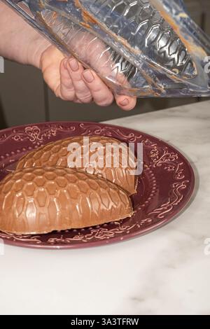 Confectioner removing chocolate Easter egg mold vertical. Stock Photo