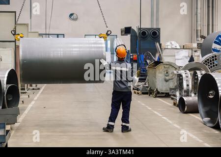 Pipe on overhead crane. Worker with remote control. Stock Photo