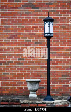 Single black metal lamp post in front of red brick wall Stock Photo
