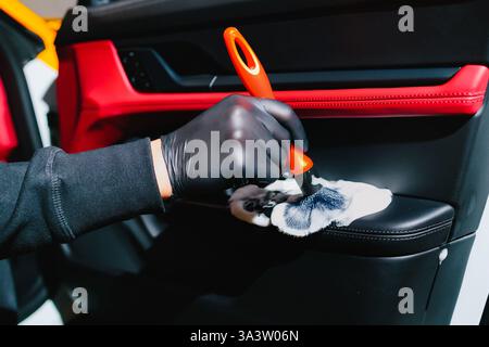 Car detailer cleans the auto door with foam brush and detergent. Process of removing dust and dirt from the car door panel at the carwash Stock Photo