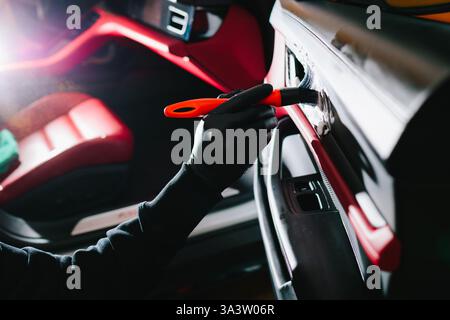 Car detailer cleans the auto door with foam brush and detergent. Process of removing dust and dirt from the car door panel at the carwash Stock Photo