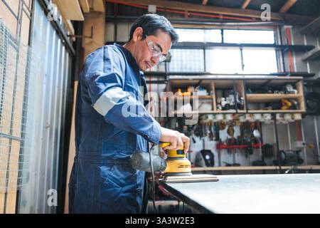 Latin carpenter and woodworker using an electric orbital sander Stock Photo