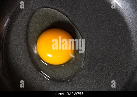 A raw egg in a non-stick pan Stock Photo