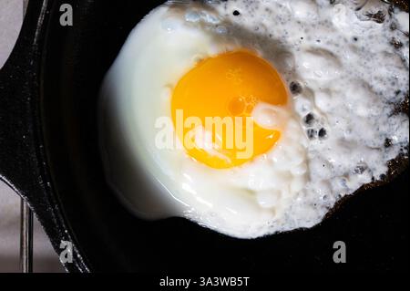 A fried egg, over easy in black cast iron pan Stock Photo