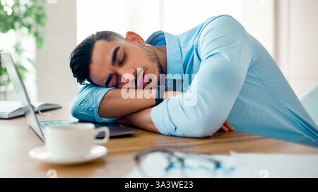 Young Arab businessman taking a break at his office desk during a busy workday Stock Photo