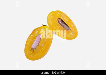 A ripe mayong chit or marian plum fruit (Bouea macrophylla), cut lengthwise, exposing its purple seed, isolated on white background Stock Photo