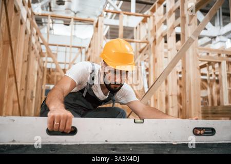 Checking the straight by using leveling tool. Industrial worker in wooden warehouse. Stock Photo