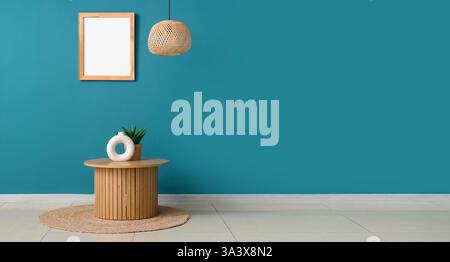 Wooden table with rug, chandelier and photo frame on dark turquoise wall. Banner for design Stock Photo