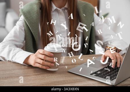 Young blogger with cup of coffee working with laptop in office Stock Photo