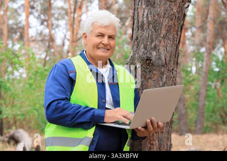 Senior forester using laptop in forest Stock Photo
