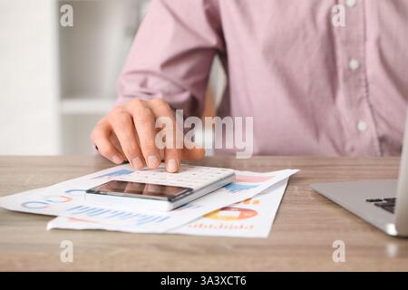 Office worker using calculator at table. Closeup Stock Photo