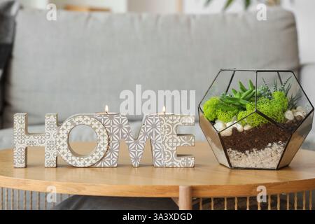 Stylish decor with burning candles and florarium on table in living room, closeup Stock Photo