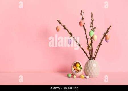 Vase with willow branches and colorful Easter eggs on yellow background Stock Photo