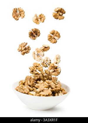 Shelled walnuts falling into bowl, isolated on white background. Stock Photo