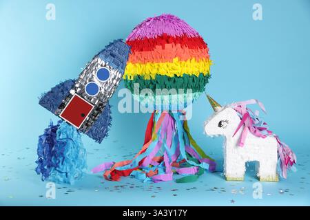 Different colorful pinatas and confetti on light blue background Stock Photo