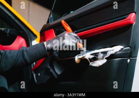 Process of removing dust and dirt from the car door panel at the carwash. Car detailer cleans the auto door with foam brush and detergent Stock Photo
