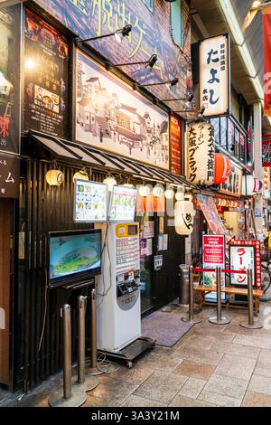 Typical traditional Japanese ramen restaurant frontage. Chochin lanterns over the narrow entrance and vending machine, Shokken, for meal tickets. Stock Photo