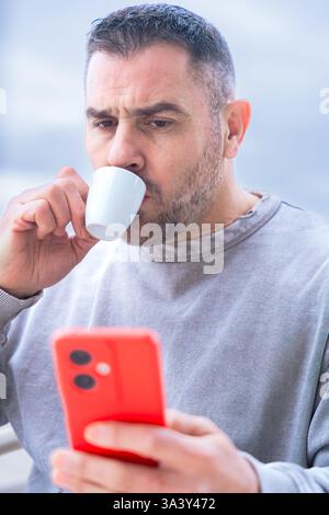 Serious man serious while typing on her smartphone at an outdoor cafe. Stock Photo