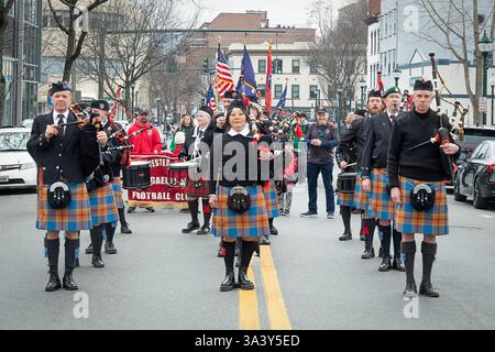 The Hudson Highlanders bagpipe and drum band in their colorful tartan skirts pause during the 2025 Peekskill St Patrick's Day Parade in Peekskill, NY. Stock Photo