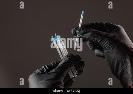 concept dry needling method. Close-up of black-gloved hands holding sterile acupuncture needles in protective tubes, symbolizing alternative medicine, Stock Photo