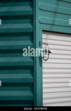 metal shipping container on end  upright painted turquoise white metal garage door and exterior light creative ways use for containers vertical image Stock Photo