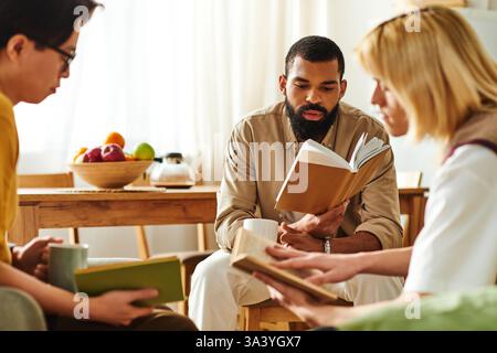 Three young men enjoy a cozy book club, sharing favorite reads and good company. Stock Photo