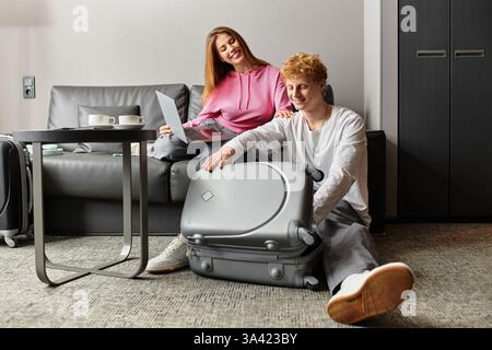 Loving couple enjoys carefree moments while preparing their suitcase for travel at a cozy hotel. Stock Photo