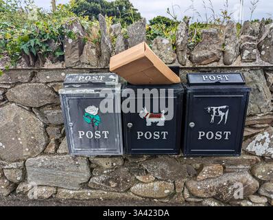 Parcels stick out from post boxes on a wall outside a number of houses. Stock Photo
