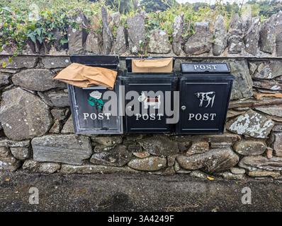 Parcels stick out from post boxes on a wall outside a number of houses. Stock Photo