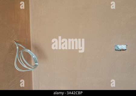 A newly plastered room with electrical switching, first  fit wiring inserts. Building work finished with a smooth flat surface of thin plaster. Stock Photo
