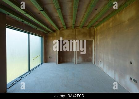 A newly plastered room with electrical switching, first  fit wiring inserts. Building work finished with a smooth flat surface of thin plaster. Stock Photo