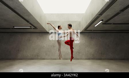 Elegant ballet dancers dancing together, leaping high gracefully to light from above and support each other against grey concrete walls. Stock Photo