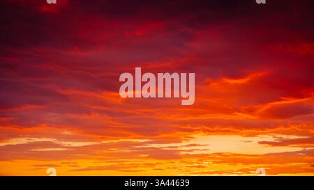 Texture and detail of a sky at sunset or sunrise, showing bright colours of orange, yellow, gold, purple, and red, for textures and backgrounds. Stock Photo