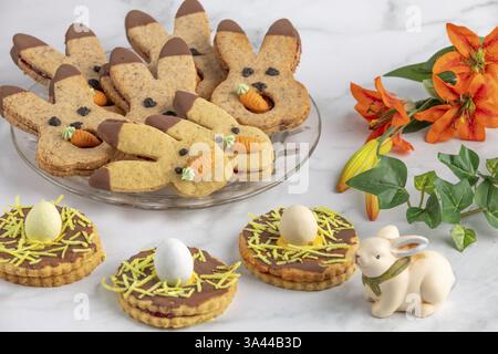 Bunny biscuits with carrots and egg decoration next to orange flowers and Easter bunny Stock Photo