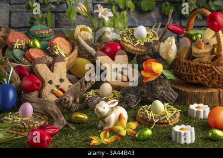 Varied Easter decorations with colourful eggs, flowers and biscuits on green grass Stock Photo