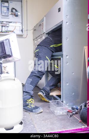 A technician repairs a system, clearly visible the person in work clothes working on technical equipment, switch cabinet construction, PV system const Stock Photo